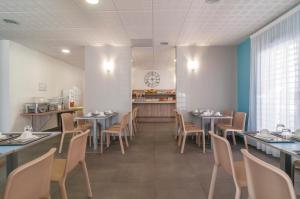 une salle à manger avec des tables, des chaises et une horloge murale dans l'établissement Appart'City Confort Perpignan Centre Gare, à Perpignan