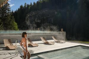 a woman in a bikini walking by a swimming pool at Hotel Bella Vista in Trafoi