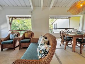a living room with wicker chairs and a table at Little Palm Penthouse in Cap Malheureux