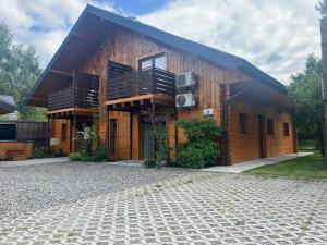 a wooden house with a balcony on a stone driveway at Noclegi Zakątek in Okuninka