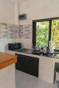 a kitchen with a sink and a stove and a window at Garden Villa in Srithanu