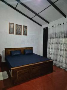 a bedroom with a bed with blue sheets and a window at Sampath State in Koslanda