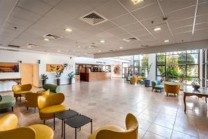 a waiting room with colorful chairs and tables at HI - Karei Deshe Hostel in Khirbet Minim