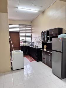 a large kitchen with a refrigerator in a room at D Anggun Homestay in Kampung Gurun
