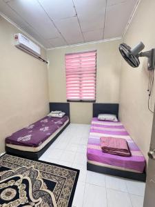 two beds in a room with a window at D Anggun Homestay in Kampung Gurun