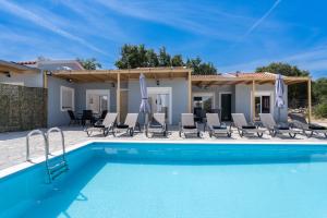 a swimming pool with chairs and a house at Studios Maximo in Karavádhos