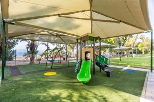 a playground with a green slide in a park at HI - Karei Deshe Hostel in Khirbet Minim