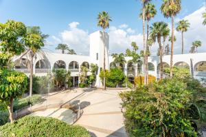 a building with palm trees and a fountain at HI - Karei Deshe Hostel in Khirbet Minim