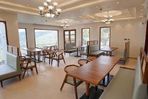 a dining room with tables and chairs and windows at Ventus Pines in Kasauli