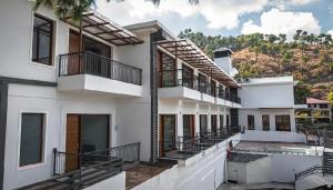 a white building with balconies and a mountain in the background at Ventus Pines in Kasauli