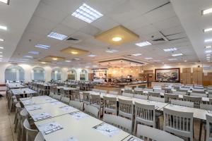 a dining room with white tables and chairs at HI - Karei Deshe Hostel in Khirbet Minim