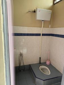 a bathroom with a toilet in a tiled room at D Anggun Homestay in Kampung Gurun +3 photos