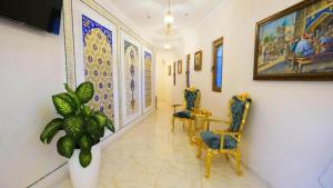 a hallway with two chairs and a painting on the wall at The Garden of Shaherezade in Bukhara