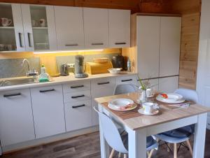 a kitchen with white cabinets and a table with chairs at Letniak pod Dębami in Grabina