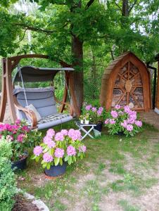 a swing in a yard with flowers and a gazebo at Letniak pod Dębami in Grabina +1 photo
