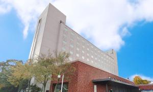 Un edificio alto y blanco con ladrillos rojos. en Hotel Grand Terrace Chitose, en Chitose