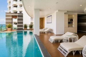 a swimming pool in a building with chairs and a building at Royal Beach View in Pattaya South +26 photos