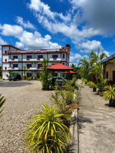 a building with a red umbrella and some plants at Huda Inn in Pantai Cenang