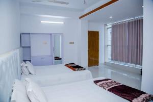 a white bedroom with two beds and a window at Dhaka Residence Hotel in Dhaka