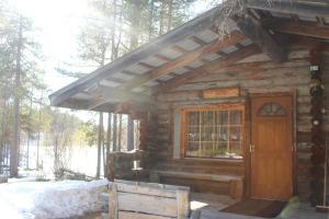 a log cabin with a wooden door in the woods at River cabin Tapio in Inari