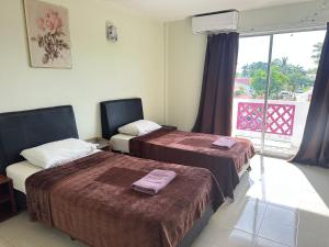 a hotel room with two beds and a window at Huda Inn in Pantai Cenang