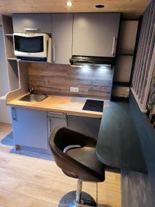 a kitchen with a desk with a chair and a microwave at Cozy studio in a mountain village in Villar-dʼArène
