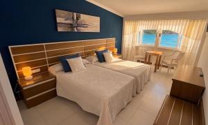 a hotel room with two beds and a window at Hotel Restaurante Playa de Estorde in Cee