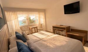 a bedroom with a bed and a television and a window at Hotel Restaurante Playa de Estorde in Cee