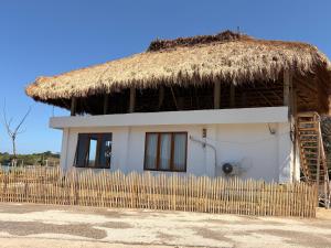 a small white house with a thatched roof at Queen house in Waikabubak