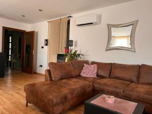 a living room with a brown couch and a mirror at Apartman Jesenjin Pobri in Volosko