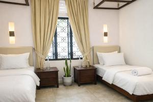 two beds in a room with a window at Rodrigo House in Colombo