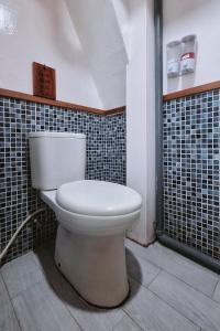 a white toilet in a bathroom with black tiles at Private Trip Labuan Bajo 2D1N in Labuan Bajo +26 photos