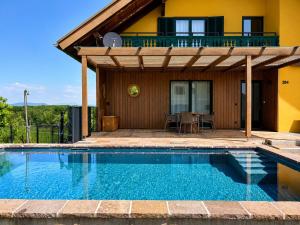 a house with a swimming pool in front of a house at Chalet mit Pool & Sauna in Ehrenhausen