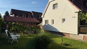 a yard with two chairs and a house at Gerbera Apartman in Ábrahámhegy