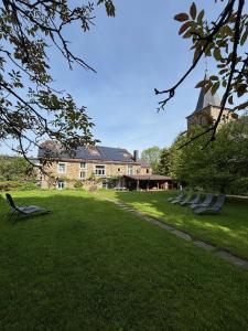 a large building with a grass yard with chairs in front at B&B Les Soigneurs in Grandmenil