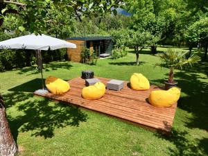 a wooden table with yellow chairs and an umbrella at FACT Apartments in Arnoldstein