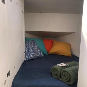 a bed in a small room with colorful pillows at Passeio diurno e hospedagem de Veleiro Maverick in Paraty