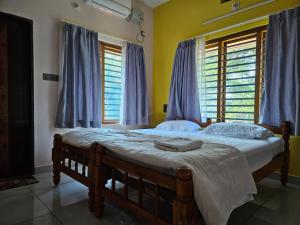 a bedroom with a large bed with blue curtains at Aadhya Serenity - Private Villa near Ecobeach Honnavar in Honāvar