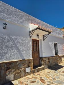 a white building with a wooden door on it at Cuevas La Cocinillas in Graena