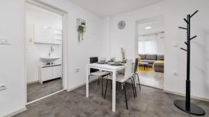 a white kitchen and dining room with a table and chairs at Apartman Grey in Jastrebarsko +12 photos