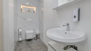 a white bathroom with a sink and a toilet at Apartman Grey in Jastrebarsko