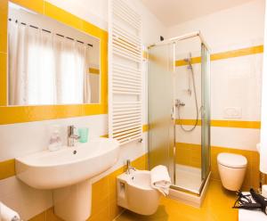 un bagno giallo e bianco con lavandino e doccia di B&B Lori a Gravedona