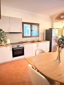 a kitchen with white cabinets and a table and a window at Casa SanGiorgio Stone Villas with Sea View in Skaltsotiánika +67 photos