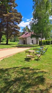 two picnic tables in the grass in front of a house at Les Gîtes du Bois de Chelles in La Chapelle-Geneste