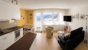a kitchen and living room with a couch and a table at Residenz Majesta Leukerbad in Leukerbad