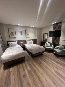 a hotel room with two beds and a chair at Lake Plaza Luxury Rooms in Borg El Arab +99 photos