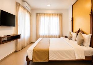 a hotel room with a large bed and a television at Bungalow Seven Mount Abu in Mount Ābu
