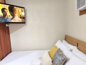 a flat screen tv hanging on a wall above a bed at WanderDesk Living-Studio Unit with Workstation in Piapi