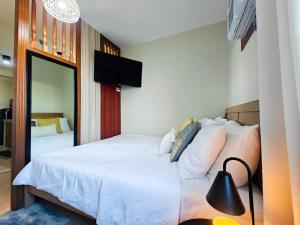 a bedroom with a white bed with a black lamp at WanderDesk Living-Studio Unit with Workstation in Piapi
