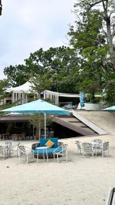 a group of chairs and an umbrella on the beach at Resort Living 1BR Corner Apartment with Balcony in Maribago